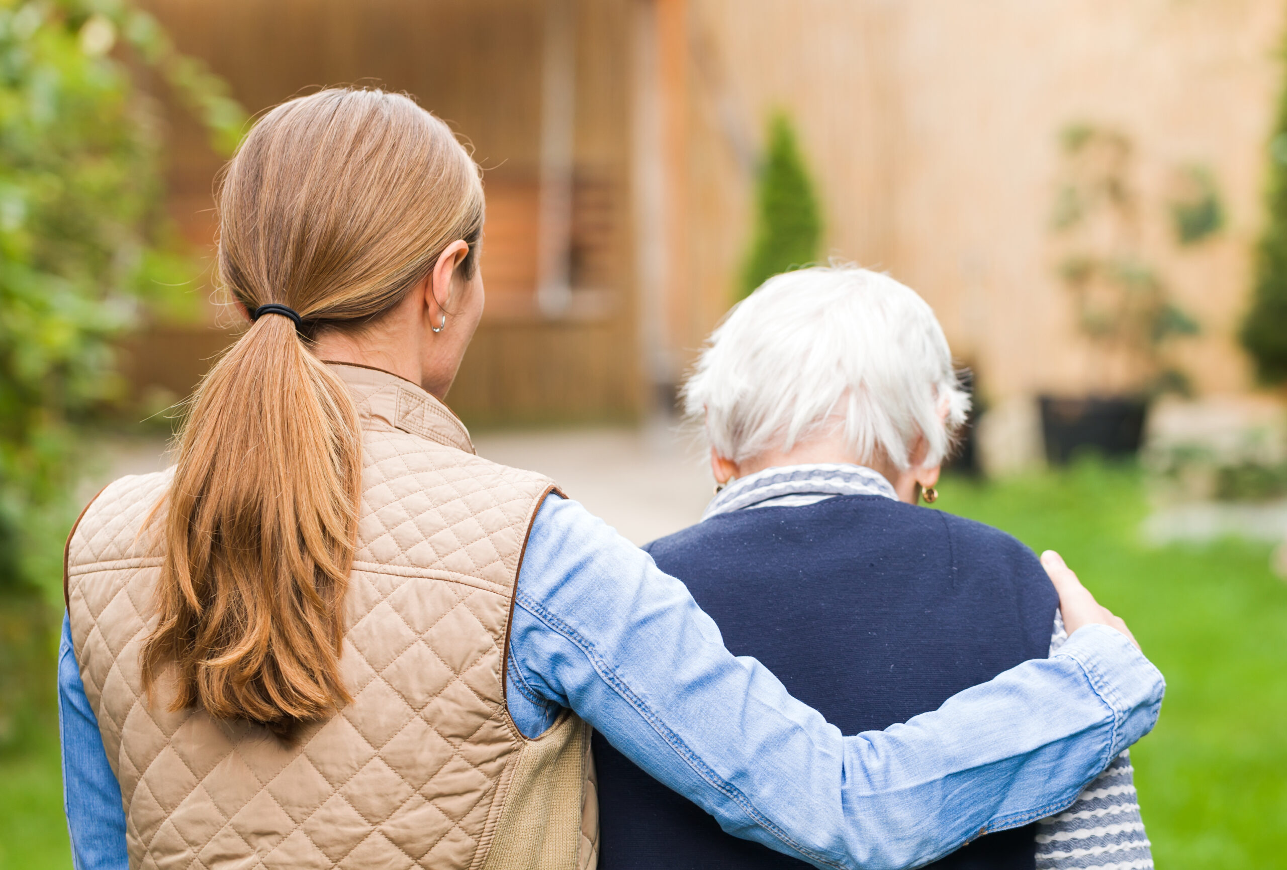 Une femme jeune qui accompagne une dame âgée, dans un jardin